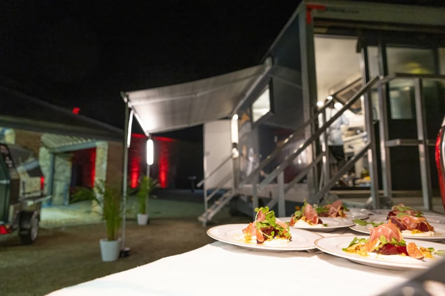 Plated canapés on an outdoor table beside Medley's mobile catering unit at night