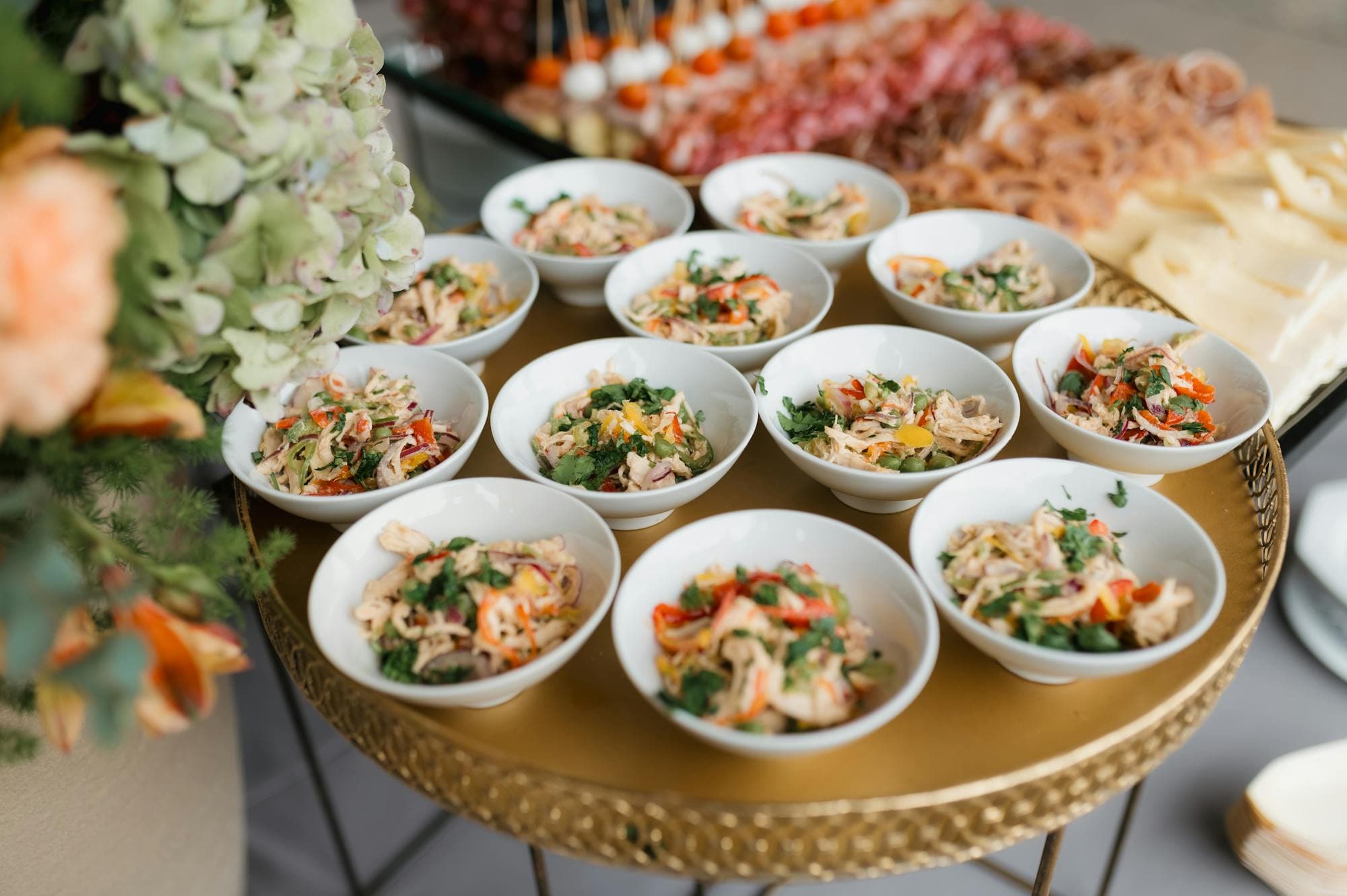 Bowls of plated salads laid out on a gold table — modern catering presentation