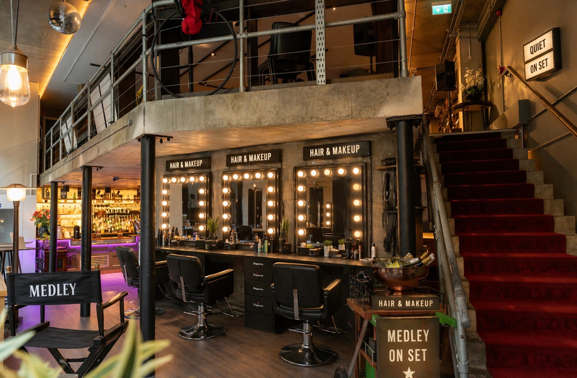 Medley's private Fleet Street venue set up as an on-set hair, makeup and holding space, with lit dressing-room mirrors and a 'Quiet on Set' sign